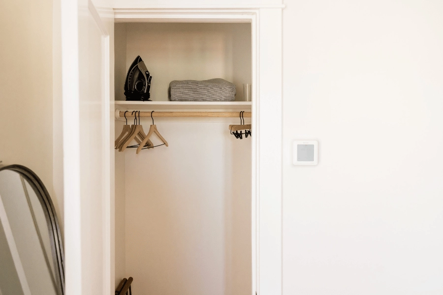 empty bedroom closet with hangers and blanket on a shelf